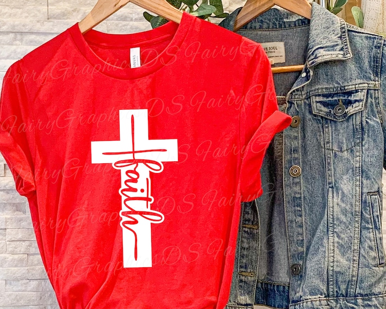 Puede incluir: Camiseta roja con una cruz blanca y la palabra "fe" escrita verticalmente dentro de la cruz.