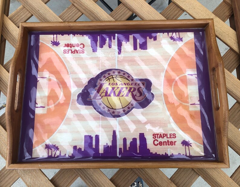 May include: A wooden serving tray with a purple and orange basketball court design. The tray features the Los Angeles Lakers logo and the text "STAPLES Center".