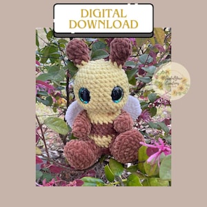 May include: A crocheted bee plush toy with brown and yellow fur, large blue eyes, and white wings. The bee is sitting on a branch of a bush with pink flowers.