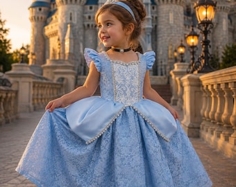 Könnte beinhalten: Ein hellblaues Kleid mit weißem Spitzenoberteil, gerüschten Ärmeln und einem weiten Rock mit Spitzenüberzug. Das Kleid ist mit weißen Perlenverzierungen entlang des Ausschnitts, der Taille und des Rocks versehen und wird mit einem passenden Stirnband kombiniert.