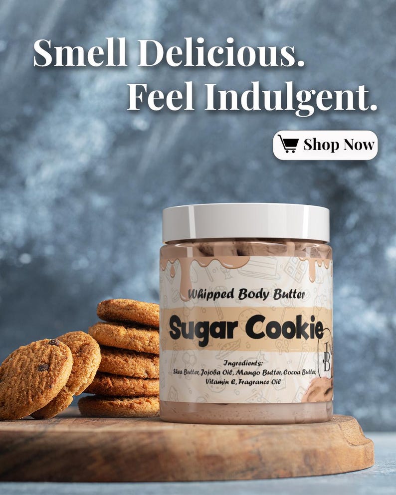 May include: A jar of "Sugar Cookie" whipped body butter with a white lid, next to a stack of chocolate chip cookies. The jar's label lists ingredients and the text "Smell Delicious. Feel Indulgent. Shop Now."