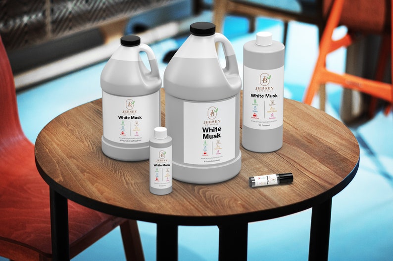 May include: Four bottles of White Musk fragrance oil in various sizes, from a small sample bottle to a large gallon jug. The bottles are on a wooden table with a black metal base.