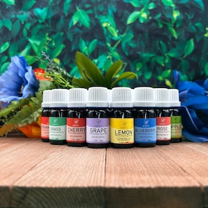 May include: Ten 10 ml bottles of essential oil in various colors and scents, including strawberry, cherry, grape, lemon, blueberry, rose, and apple. The bottles are labeled with the scent and the brand name "Jersey's".