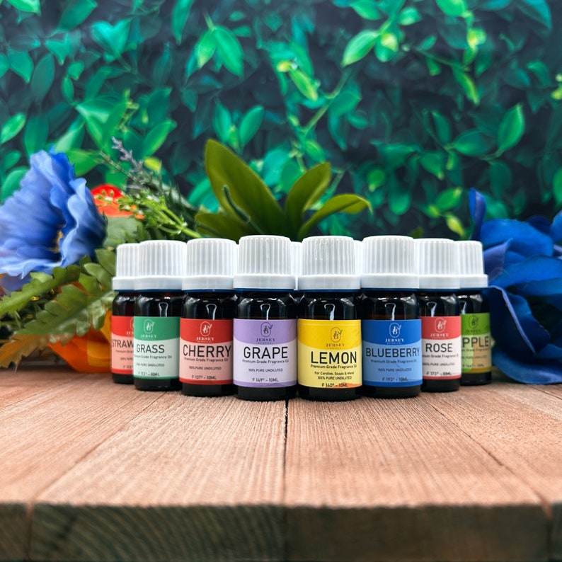 May include: Ten 10 ml bottles of essential oil in various colors and scents, including strawberry, cherry, grape, lemon, blueberry, rose, and apple. The bottles are labeled with the scent and the brand name "Jersey's".