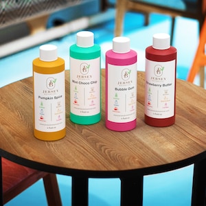 Może przedstawiać: Cztery 4-uncyjne butelki olejku zapachowego z etykietami przedstawiającymi logo Jersey Botanicals i r&oacute;żnymi zapachami: Pumpkin Spice, Mint Choco Chip, Bubble Gum i Strawberry Butter.