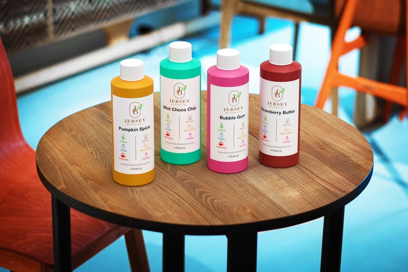 Może przedstawiać: Cztery 4-uncyjne butelki olejku zapachowego z etykietami przedstawiającymi logo Jersey Botanicals i r&oacute;żnymi zapachami: Pumpkin Spice, Mint Choco Chip, Bubble Gum i Strawberry Butter.