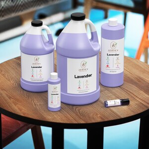 Op de afbeelding: Vier flessen lavendelolie in verschillende maten, van een klein rolletje tot een grote gallonkan. De flessen zijn allemaal paars en hebben een wit etiket met de tekst "Jersey Botanicals Lavender" erop.