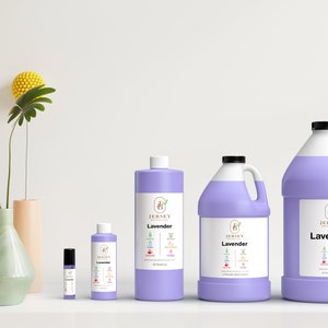 Op de afbeelding: Vier flessen lavendelolie in verschillende maten, van een klein rolletje tot een grote gallonkan. De flessen zijn allemaal paars en hebben een wit etiket met de tekst "Jersey Botanicals" en "Lavender" erop.
