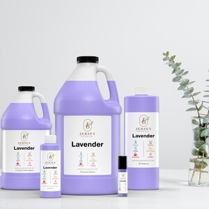 Op de afbeelding: Vier flessen lavendelolie in verschillende maten. De flessen zijn paars en hebben een wit etiket met de tekst "Jersey Botanical" en "Lavender". De flessen zijn in een rij van links naar rechts gerangschikt, met de kleinste fles links en de grootste fles rechts.