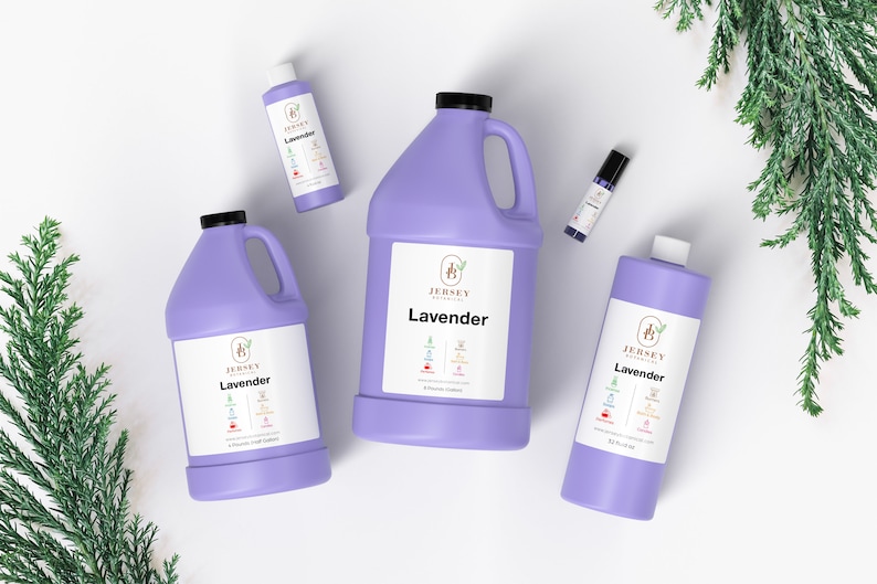 Op de afbeelding: Vier flessen lavendelolie in verschillende maten. De flessen zijn paars en hebben een wit etiket met de tekst "Jersey Botanicals Lavender". De flessen zijn gerangschikt op een wit oppervlak met een takje groen blad op de achtergrond.