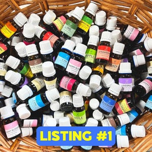 May include: A basket filled with a variety of small glass bottles with white caps. The bottles are labeled with different essential oil names, such as "Lime", "Strawberry", "Apple", "Cherry Blossom", "Blueberry", and "Love Spell".