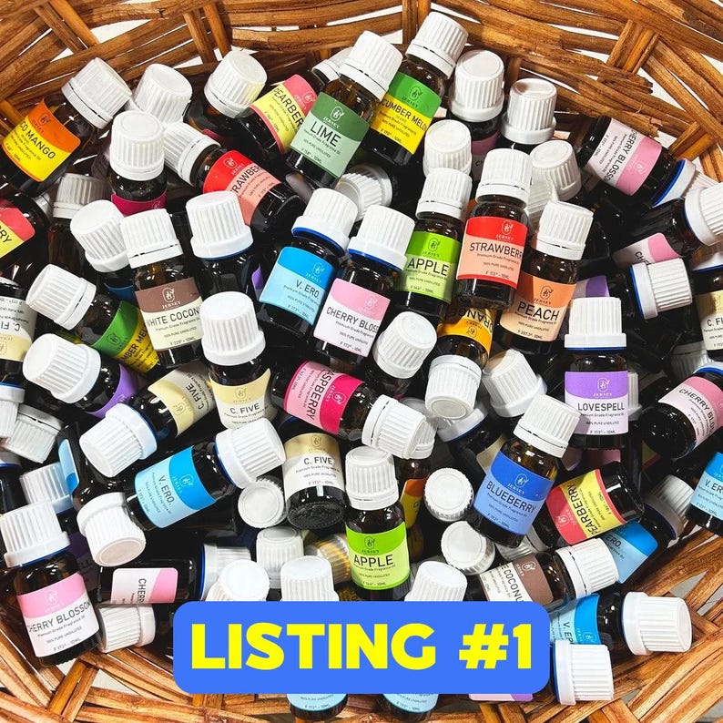 May include: A basket filled with a variety of small glass bottles with white caps. The bottles are labeled with different essential oil names, such as "Lime", "Strawberry", "Apple", "Cherry Blossom", "Blueberry", and "Love Spell".