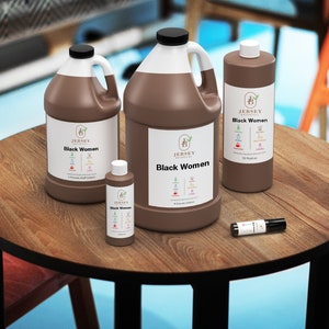 May include: Four brown bottles of essential oil on a wooden table. The bottles are labeled "Jersey Botanicals Black Women" and contain 1 oz, 4 oz, 12 oz, and 1/2 oz of oil.