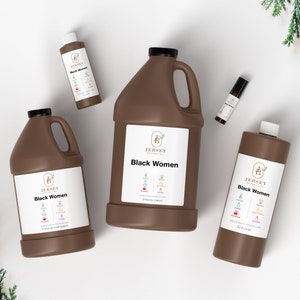 May include: Four brown bottles of "Black Women" essential oil blend by Jersey Botanicals. The bottles are in different sizes, including a small roll-on bottle, a small bottle, a medium bottle, and a large bottle. The bottles are on a white surface with green foliage in the background.