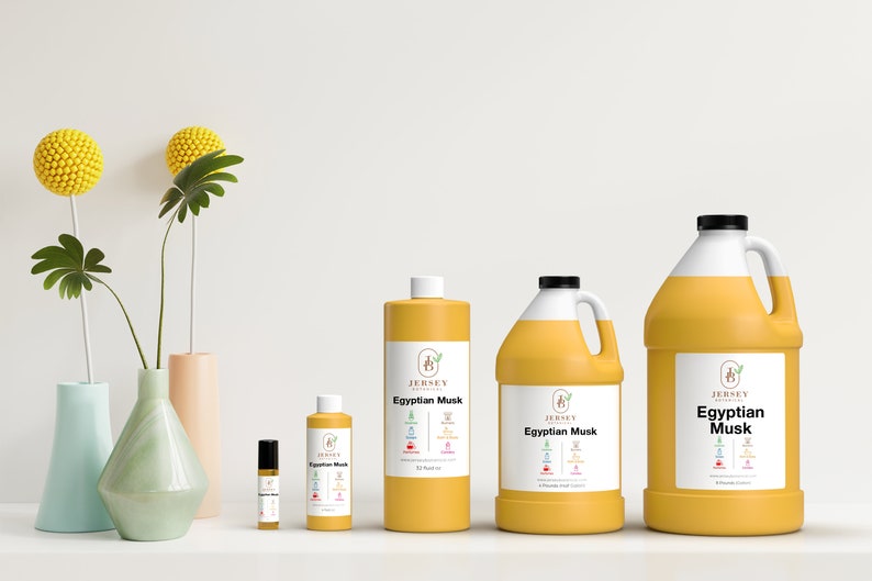May include: Four bottles of Egyptian Musk essential oil in different sizes. The bottles are yellow and have a white label with the text "Jersey Botanicals Egyptian Musk" on them. The bottles are arranged in a row from smallest to largest.