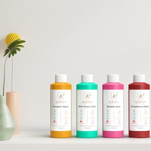 Może przedstawiać: Pięć butelek płynu z etykietami z napisem "Jersey" i r&oacute;żnymi smakami: Pumpkin Spice, Mint Choco Chip, Bubble Gum i Strawberry Butter. Butelki są ustawione na białej powierzchni.