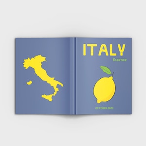 Puede incluir: Un libro azul con la palabra "ITALIA" en letras amarillas y la palabra "Essence" en letras verdes. El libro tiene un contorno amarillo de Italia en el lado izquierdo y un lim&oacute;n amarillo con una hoja verde en el lado derecho. El texto "OCTUBRE 2023" est&aacute; en la parte inferior del lado derecho.