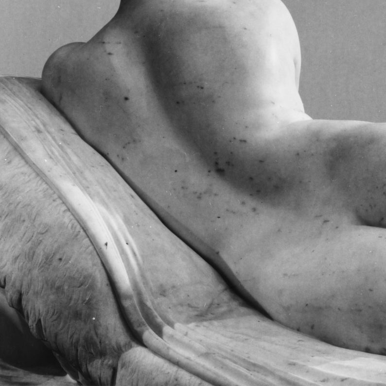 Puede incluir: Primer plano de una escultura de m&aacute;rmol de una figura femenina reclinada. La escultura est&aacute; en blanco y negro, y la espalda de la figura es visible. La escultura est&aacute; sobre una superficie texturizada.