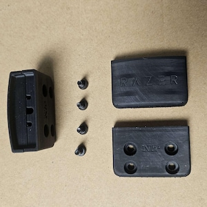 May include: Black plastic case with four screw holes and the text "Razer" on the top. The case has a slot for a small object. Five black screws are included.