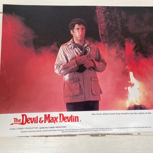 May include: A movie poster for the film "The Devil & Max Devlin" featuring actor Elliott Gould in a scene with fire and smoke. The text on the poster reads "Max Devin (Elliott Gould) finds himself in the fiery depths of Hell."