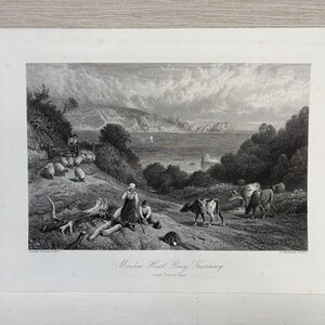 May include: Black and white landscape print depicting a coastal scene with sheep, cows, and figures. The print features a detailed illustration of a hillside with grazing animals, a woman and child, and a view of the sea. The title "Moulin Huet Bay, Guernsey" is at the bottom.