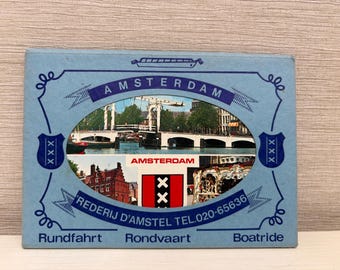 May include: A blue and white postcard with a picture of a bridge in Amsterdam. The postcard says "Amsterdam" and "Rederij D'Amstel Tel. 020-65636" and has the words "Rundfahrt", "Rondvaart", and "Boatrides" at the bottom.