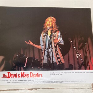 May include: A black and white photo of a woman singing on stage. The text "The Devil & Max Devlin" is at the bottom of the photo.