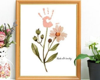 May include: A framed print of a pink handprint flower with green leaves and the text "Made with love by" in a brown frame.