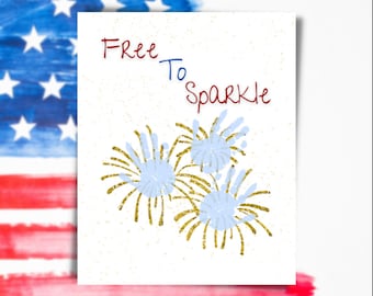 May include: A white card with the text "Free To Sparkle" in red and blue lettering. The card features a blue and gold glitter firework design.