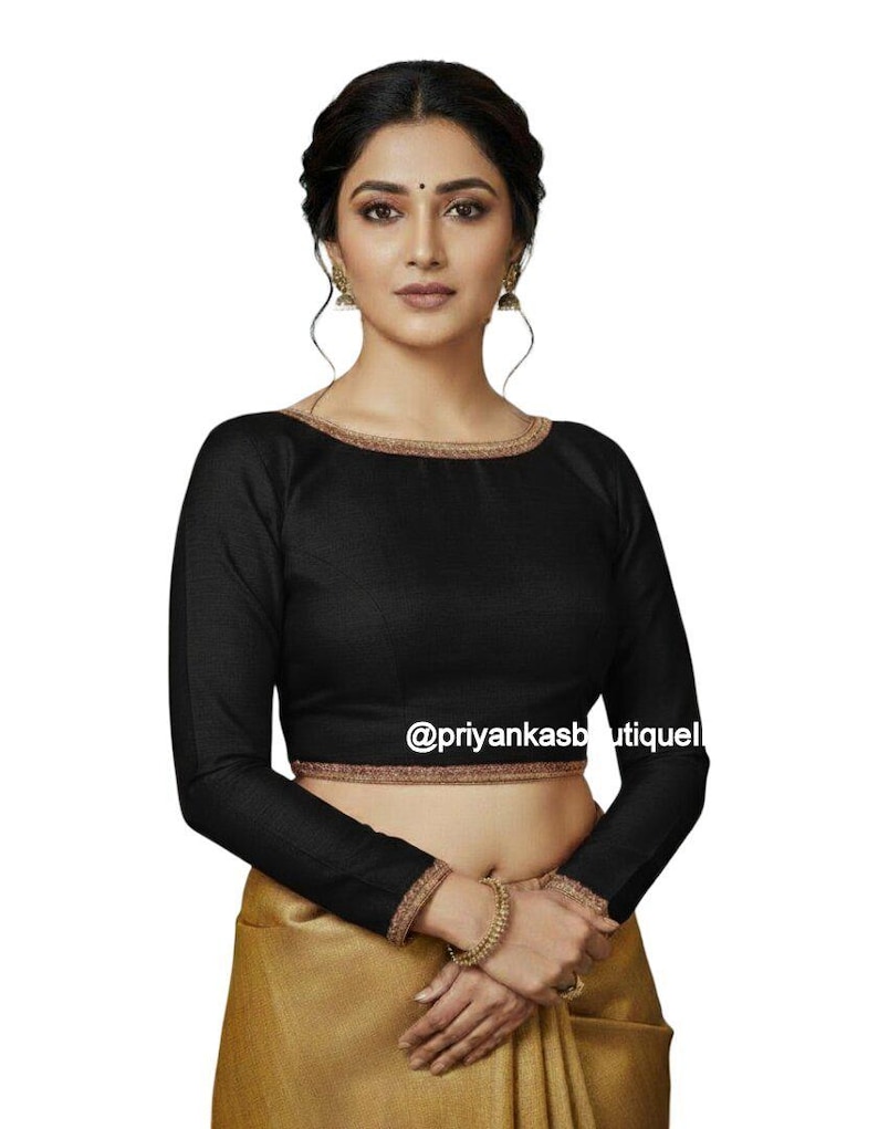 May include: Black long-sleeve blouse with gold trim around the neckline and cuffs. The blouse has a scoop neckline and is paired with a gold-colored skirt. The text "@priyankasboutiquel" is visible on the blouse.