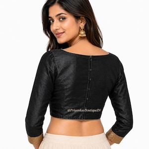 May include: Black long-sleeve blouse with a scoop neckline and gold trim on the sleeves. The blouse has a row of buttons down the back. The text "@PriyankasBoutiqueN" is visible on the blouse.
