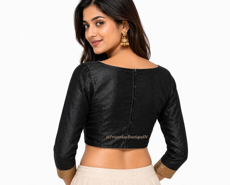May include: Black long-sleeve blouse with a scoop neckline and gold trim on the sleeves. The blouse has a row of buttons down the back. The text "@PriyankasBoutiqueN" is visible on the blouse.