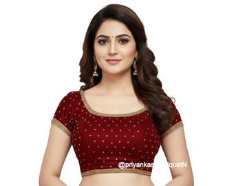 May include: A maroon short-sleeved blouse featuring a scoop neckline and gold-toned trim along the edges. The fabric is adorned with a repeating pattern of small, light-coloured dots. The text @priyankasqueIN is visible on the lower right side.