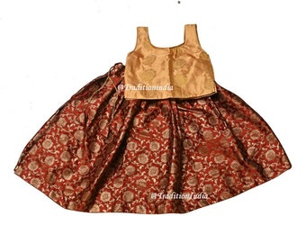Könnte beinhalten: Ein roter und goldener Brokatrock mit passendem goldenen ärmellosem Oberteil. Der Rock hat ein Blumenmuster und das Oberteil hat ein schlichtes Design.
