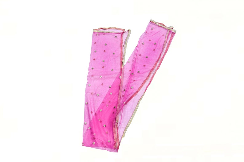 Op de afbeelding: Een roze, doorschijnende sjaal met gouden rand en zilveren pailletten. De sjaal is dubbelgevouwen en de uiteinden overlappen elkaar.