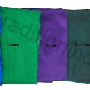 May include: Five fabric swatches in vibrant colors: blue, green, purple, dark green, and red. Each swatch is labeled with its respective color name in black text. The fabrics appear to be smooth and possibly silk or satin.