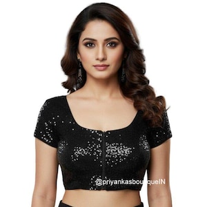 May include: A black sequined crop top with a scoop neckline and short sleeves. The top features a zip closure and is adorned with silver sequins. The text "@priyankasboutiqueIN" is visible at the bottom of the garment.
