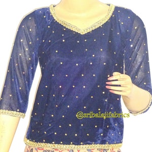 Puede incluir: Una blusa de terciopelo azul marino con ribetes dorados y pedrería. La blusa tiene cuello en V y mangas tres cuartos. El texto "@sribalajifabrics" es visible en la parte delantera de la blusa.