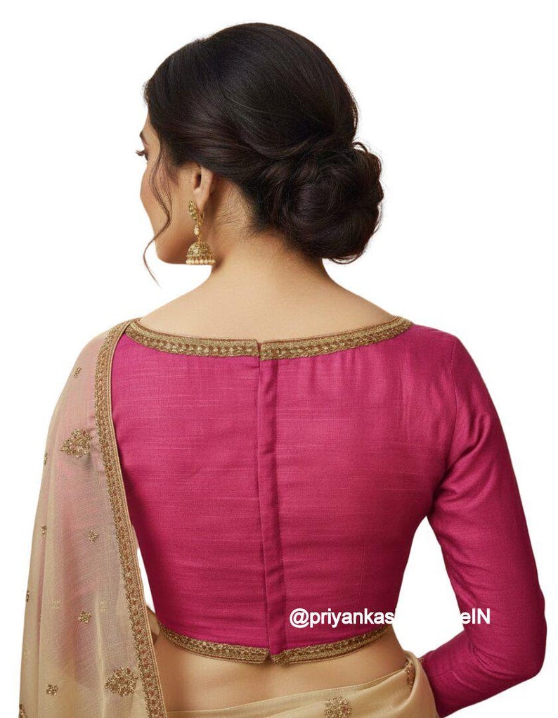 May include: A magenta-colored blouse with long sleeves and a boat neckline, trimmed with gold embroidery. The back of the blouse is visible, with a central seam. A portion of a beige sari with gold embroidery is also visible.