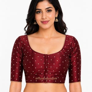 Könnte beinhalten: Eine weinrote Bluse mit rundem Ausschnitt und Dreiviertelärmeln. Die Bluse ist mit kleinen, weißen Punkten und goldenen Verzierungen versehen. Der Text "@PriyankasBoutiqueIN" ist sichtbar.