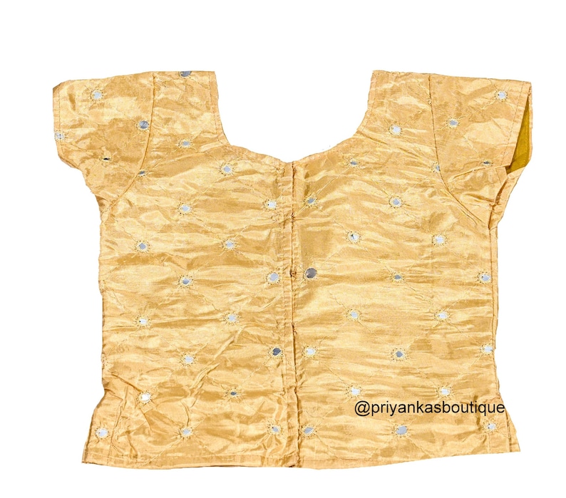 Op de afbeelding: Een gouden, mouwloze blouse met een ronde hals en korte mouwen. De blouse is versierd met kleine ronde spiegelversieringen. De tekst "@priyankasboutique" staat gedrukt in de rechterbenedenhoek van de blouse.