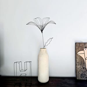 Een enkele sierlijke draadleliebloem als statement voor een minimalistische topvaas