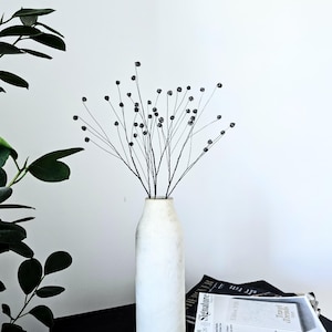 Een set van drie draadtakjes gipskruid als subtiel, minimalistisch woonaccessoire.