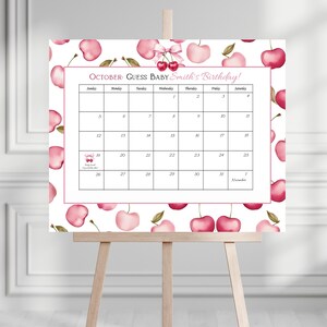 May include: A calendar on an easel with a cherry theme. The calendar is for October, with the text "October: Guess Baby Smith's Birthday!" The calendar has a pink border and is decorated with watercolor cherries.