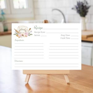K&ouml;nnte beinhalten: Eine wei&szlig;e Rezeptkarte mit einem gr&uuml;nen Titel "Rezept" und einer Aquarell-Illustration eines Kochhuts, eines Nudelholzes und Blumen. Die Karte hat Linien zum Schreiben von Zutaten, Anweisungen, Rezeptquelle, Portionen, Vorbereitungszeit und Kochzeit.