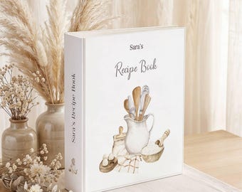 May include: A white three-ring binder with the text Sara's Recipe Book printed on the front and spine. The cover features a watercolor illustration of a white pitcher, wooden kitchen utensils, a bowl of flour, and eggs on a cloth.