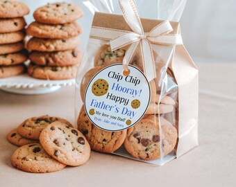 May include: A clear plastic bag filled with chocolate chip cookies, tied with a beige ribbon and a round tag that reads: Chip Chip Hooray! Happy Father's Day, We love you Dad! Ryan, Jake and Sara. A stack of cookies sits nearby on the table.