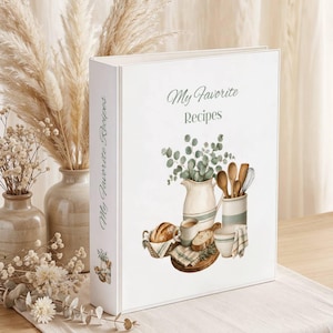 May include: A white recipe binder with the text My Favorite Recipes printed on the front cover. The cover features a watercolor illustration of a pitcher, a bowl, a basket of bread, and kitchen utensils with green eucalyptus sprigs.
