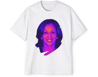 Op de afbeelding: Wit T-shirt met een kleurrijk, gestileerd portret van een vrouw met donker haar en een glimlach. Het portret gebruikt een kleurengradiënt van paars, roze en oranje. Het T-shirt is een klassieke ronde hals.