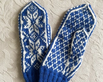 May include: A pair of blue and white knitted mittens with a snowflake pattern. The mittens have a blue cuff.